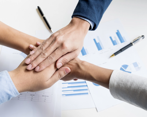 Team putting their hands together over business charts